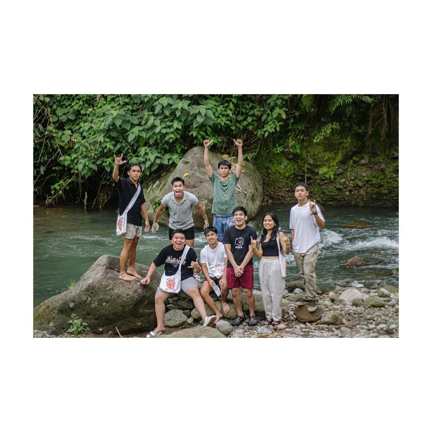 The SUL.OB team together beside a river, with several members carrying tote bags.
