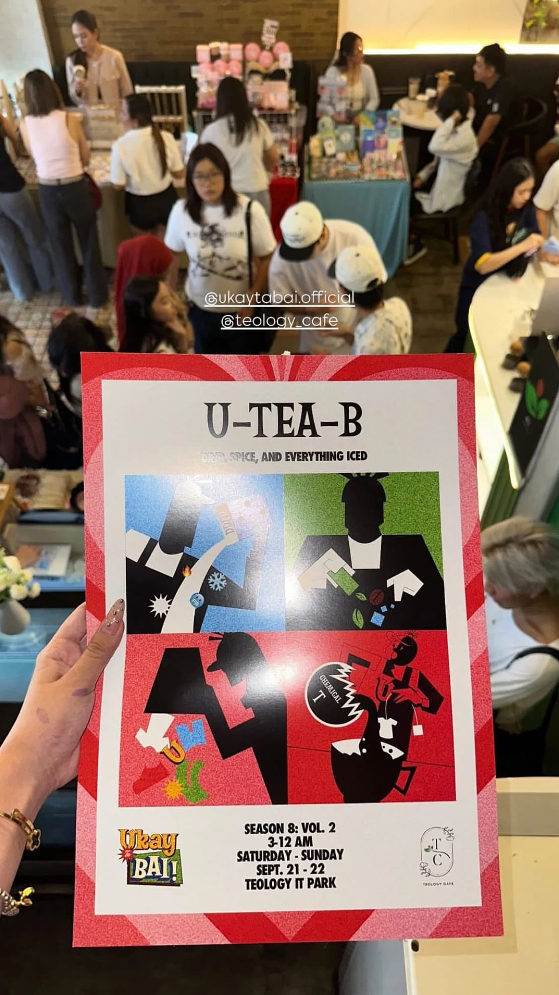 A hand holding a U-Tea-B and Ukay Ta Bai event flyer in front of the venue.